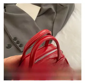 Detail of red patent leather bowling bag featuring high-gloss finish and metal zipper