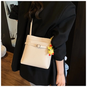Détail du sac seau beige texture litchi avec un pendentif petit canard jaune mignon