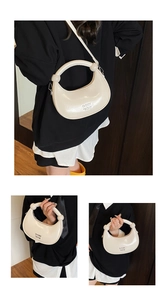 Detail view of cream crescent bag in glossy patent leather with silver hardware accents