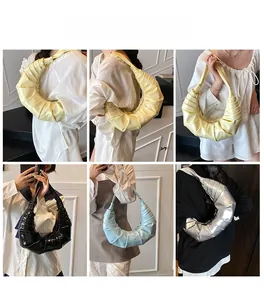 Detailed view of fashionable pleated croissant bags in multiple glossy finishes and colors