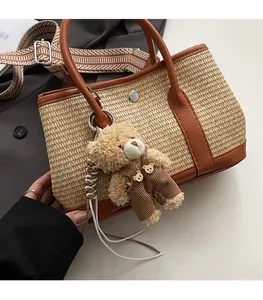 Détail du sac seau en paille tressée avec garniture en cuir et pendentif ours en peluche