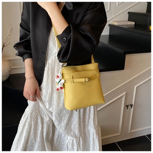 Détail d'un sac seau en cuir grainé jaune vif orné d'un charmant petit canard blanc