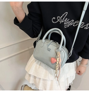 Vue détaillée du sac à main bleu clair en cuir avec pendentif cœur et breloque tressée