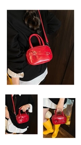 Red glossy leather bowling bag with bow buckle detail and adjustable shoulder strap
