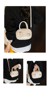 Detail view of cream patent mini bowling bag featuring bow tie design and metal buckles
