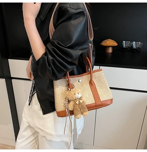Détail d'un sac seau en paille avec garniture en cuir et breloque ours en peluche