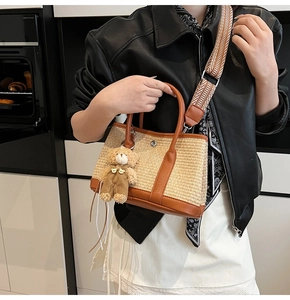 Détail du sac seau en paille avec garniture en cuir et large bandoulière de style ethnique
