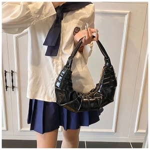 Close-up of black glossy patent leather hobo bag with pleated texture and golden zipper