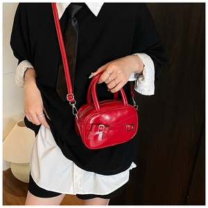 Red mini bowling bag with bow detail and glossy finish shown on model as a crossbody