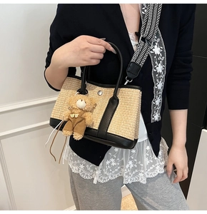 Détail du sac cabas en paille tressée avec poignées en cuir noir et bandoulière rayée