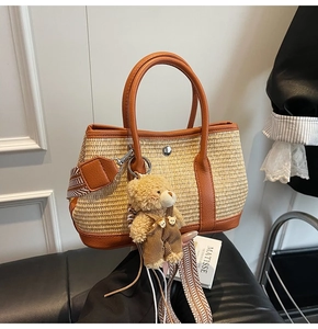 Détail du sac seau en paille avec poignées en cuir et pendentif ours décoratif