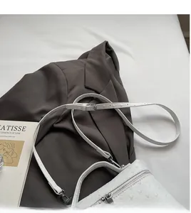 Detailed macro shot of white ostrich texture leather bag with silver zipper and shoulder strap
