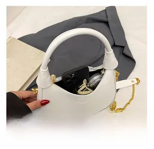 Detail of the white patent leather hobo bag interior capacity with golden chain strap