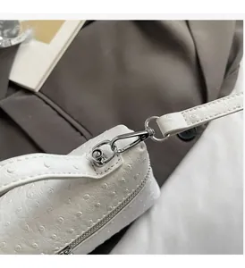 Close-up of pearl white ostrich embossed faux leather bag with shiny silver hardware