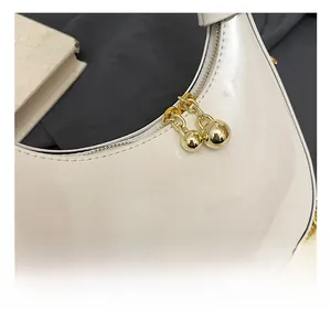 Detail of white glossy crescent bag featuring golden ball zipper and chain strap