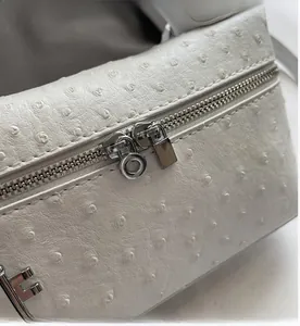 Detail of white ostrich pattern leather with smooth silver double zipper and metal logo