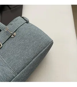 Detailed view of light blue denim fabric texture and silver buckle on the handbag