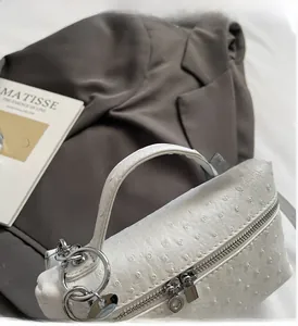 Detailed view of white ostrich pattern leather handbag with silver double zippers