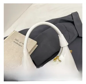 Detail of white glossy crescent handbag with gold chain and spherical metal zipper pull