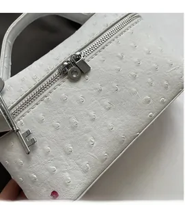 Macro shot of white ostrich pattern leather texture with key charm and silver zipper detail