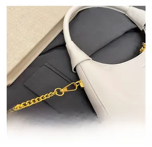 Close-up of premium gold metal clasp and chain on a white patent leather handbag