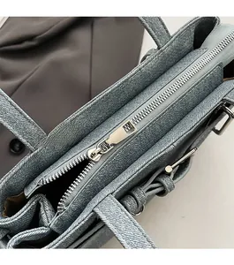 Detail of smooth silver zipper closure on blue denim texture vintage motor handbag