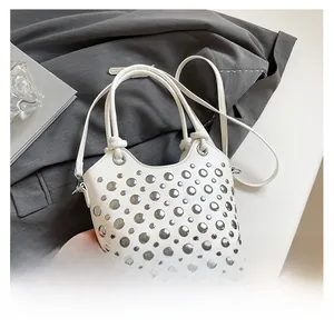 Detail of white leather bucket bag featuring silver rivet accents and knotted handle
