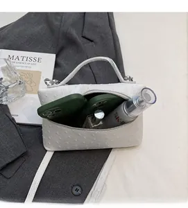 Internal capacity of white ostrich pattern handbag showing space for phone and perfume
