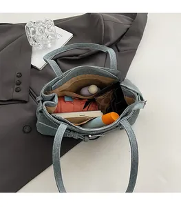 Spacious interior of denim satchel bag showing compartments for phone and daily items