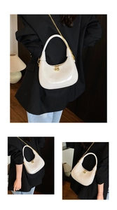 Detail of white glossy patent leather crescent bag with gold chain and bead zipper pull