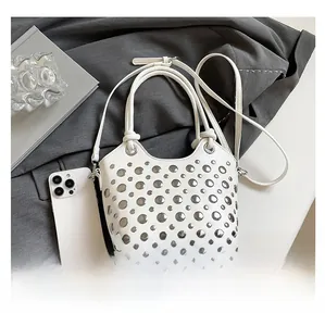 Detail view of white leather bucket bag with silver metal rivets and mobile phone reference