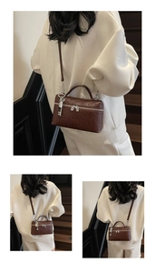 Detail of dark brown ostrich texture crossbody bag with silver lock and key charm