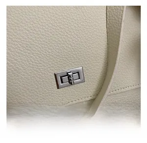 Detailed close-up of a silver rectangular metal turn-lock on off-white lychee leather bag