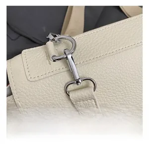 Macro detail of silver-tone metal hook and D-ring on ivory lychee texture leather bag