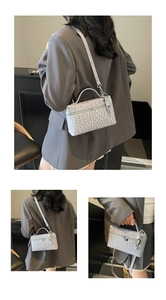Detail of grey ostrich-pattern handbag with top handle and silver lock accessory