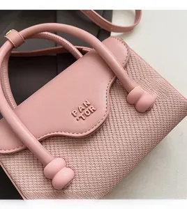 Gros plan du sac à main tissé rose avec rabat en cuir lisse et logo en relief