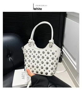Detail view of a white bucket bag with silver metal studs and polished leather texture