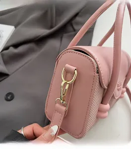 Détail du sac à main en cuir rose avec texture tissée et boucle en métal doré