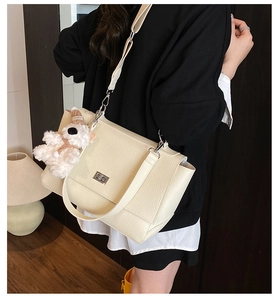Detail of cream white leather satchel showing silver twist lock and plush bear charm