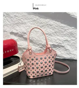 Detailed view of pink bucket bag with silver eyelets and knotted handles on black desk
