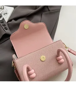Détail d'un sac à main tressé rose avec fermoir magnétique doré et poignée perlée