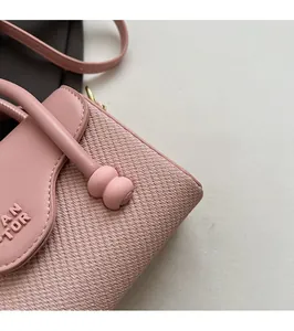 Détail du sac carré rose de style français montrant le cuir et le logo gaufré