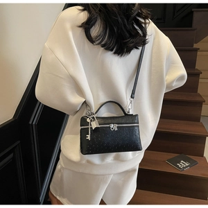 Detail of ostrich texture handbag with silver padlock charm and removable strap