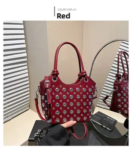Close-up of red bucket bag with silver studs, handles and adjustable shoulder strap