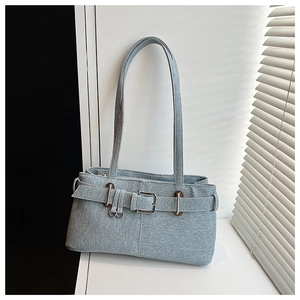 Detail of light blue denim shoulder bag featuring a vintage metal buckle and fabric texture