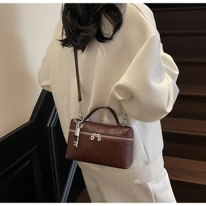 Detailed close-up of dark brown ostrich texture crossbody bag with silver key pendant