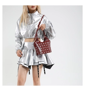 Detail of burgundy leather bucket bag with dense silver metal rivets and punk style finish