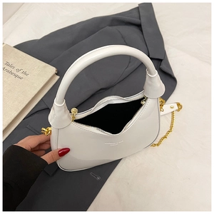 Detail of white glossy crescent hobo bag featuring thick handle and gold chain strap