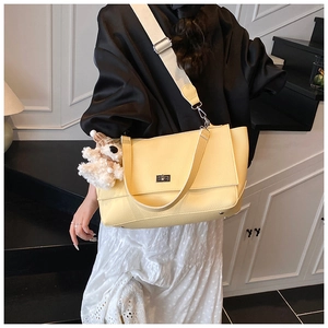 Detail of yellow lychee leather bag with silver twist lock and plush bear charm
