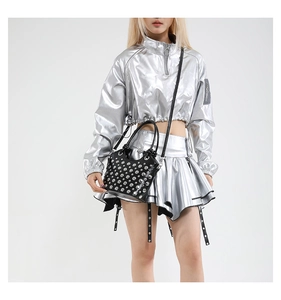 Dettaglio borsa a secchiello punk nera con borchie indossata con outfit metallico